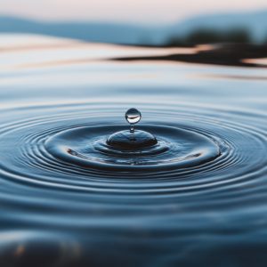 A single drop of water creating ripples on a calm surface