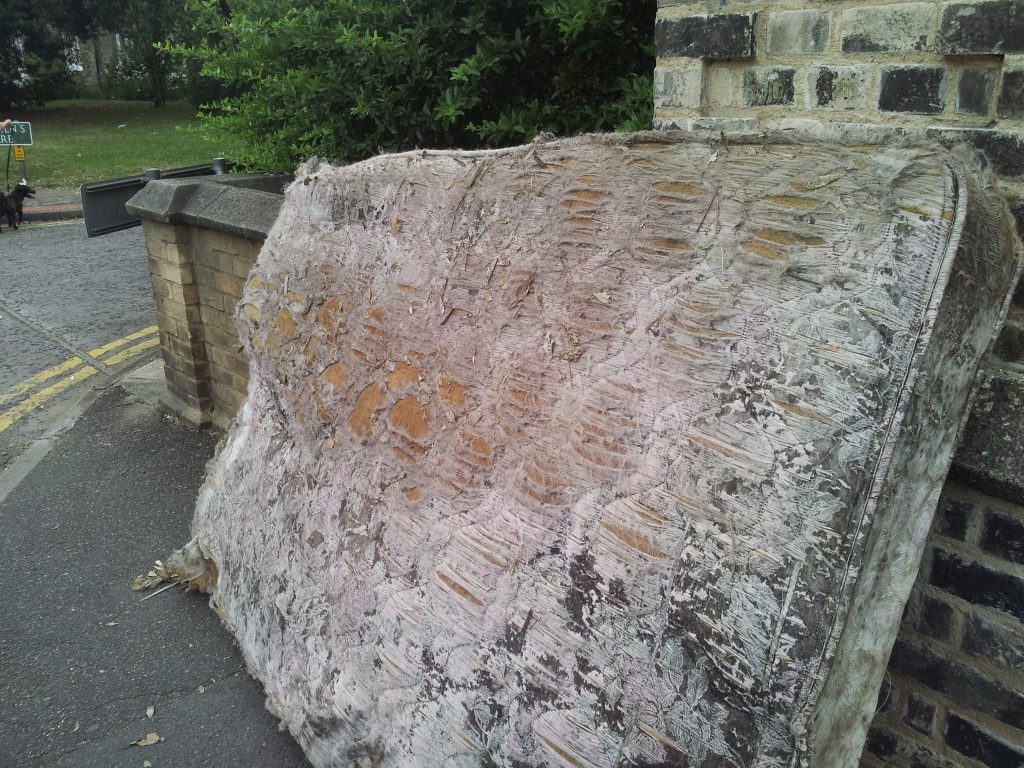 Stripped and discarded mattress leaning against a brick wall on a South London street