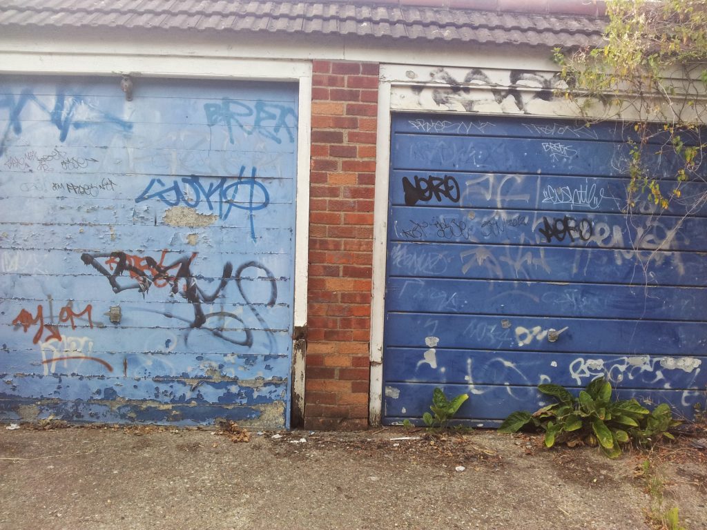 Two blue garage doors covered in graffiti in South London